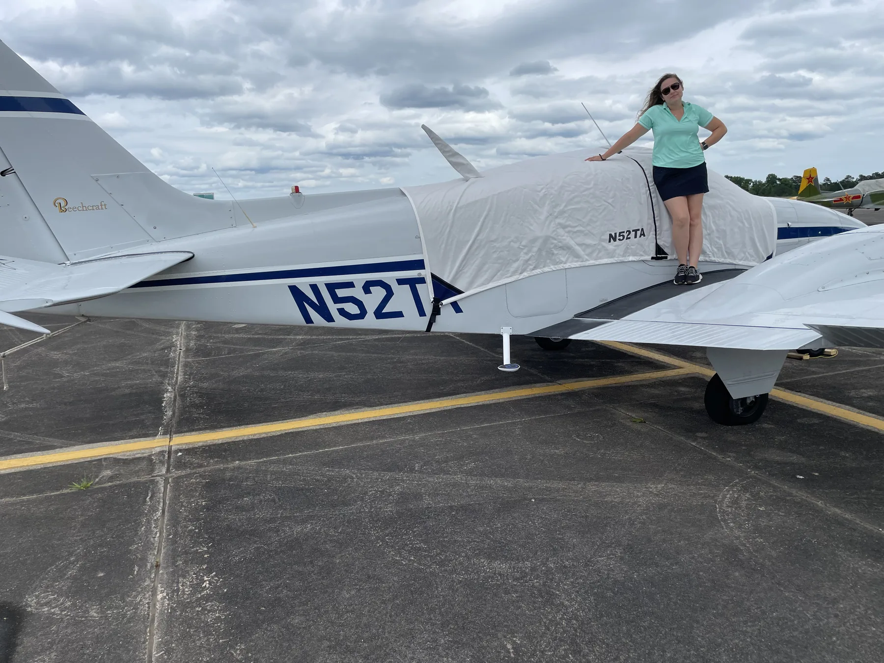 Ally standing on the wing of the family Baron on the ramp, white with a blue stripe